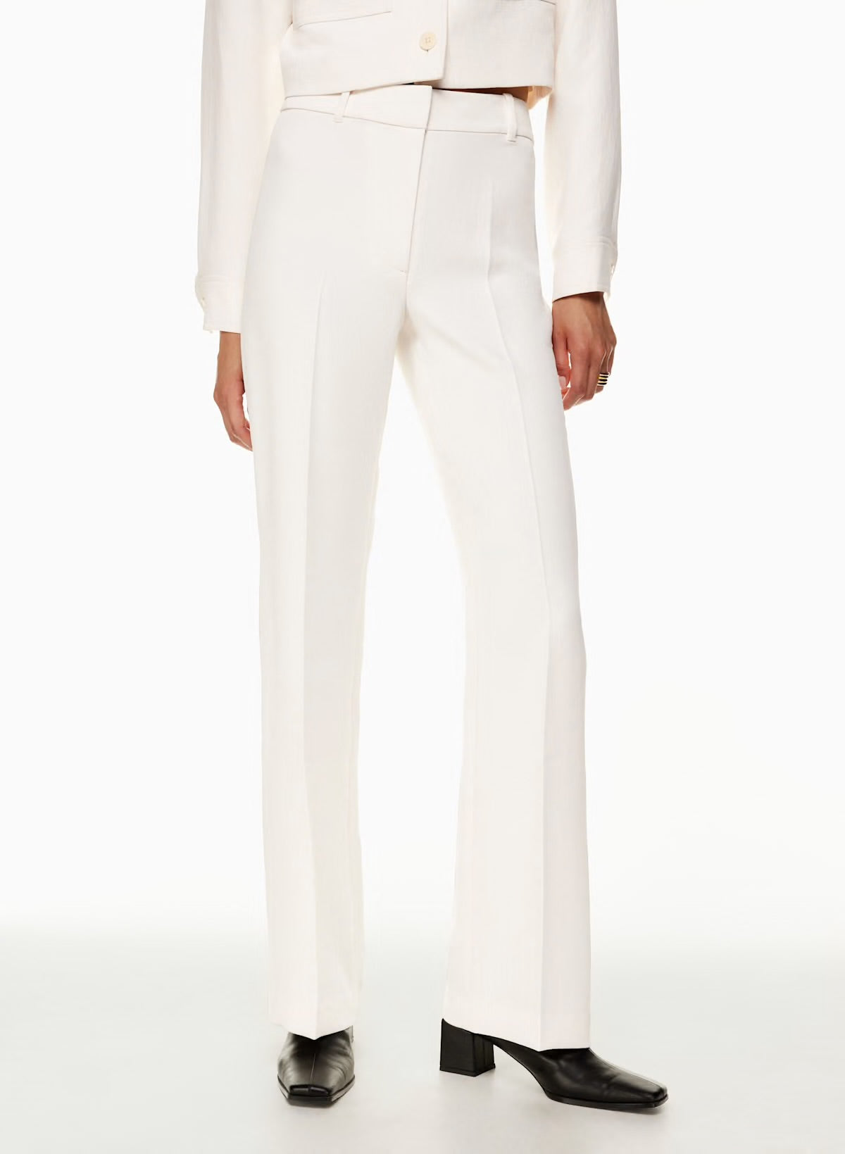 Model wearing Siamo Firenze white Contour Flare Pants with a structured high-waist fit, center crease, and soft flare, styled with black square-toe boots.